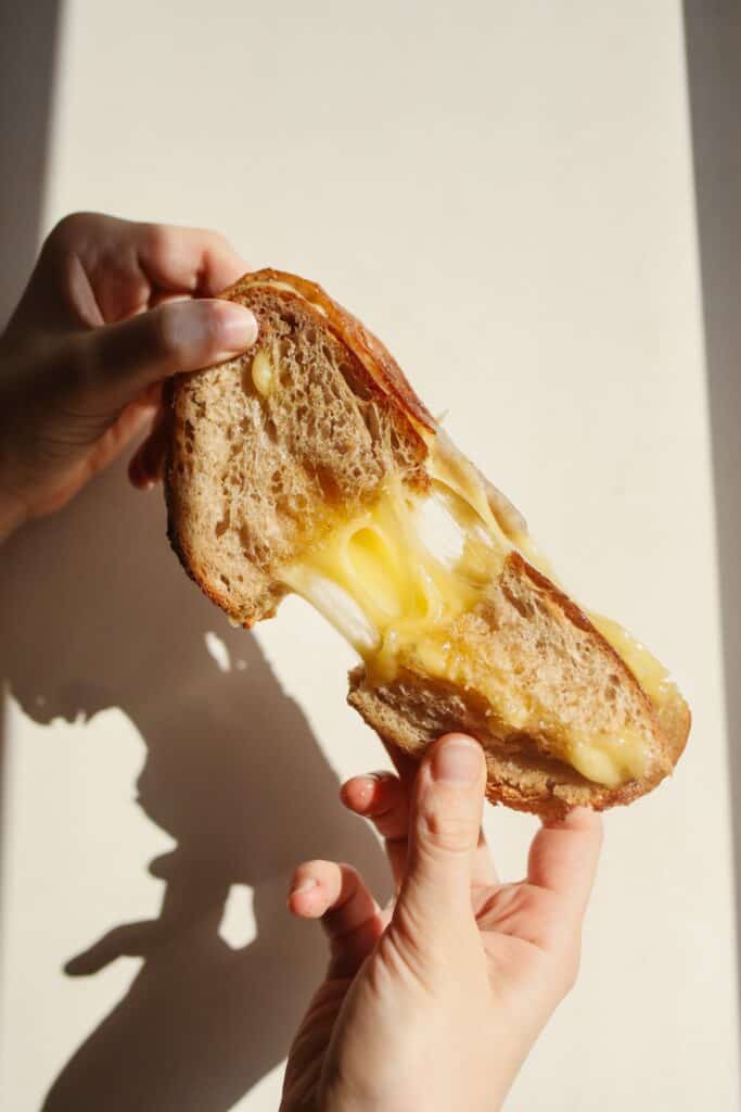 Two hands pulling a grilled cheese sandwich apart that resulted in an epic cheese pull.