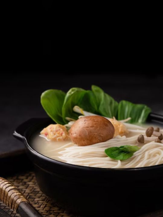 a bowl of warm cooked rice noodles topped with ginger and basil
