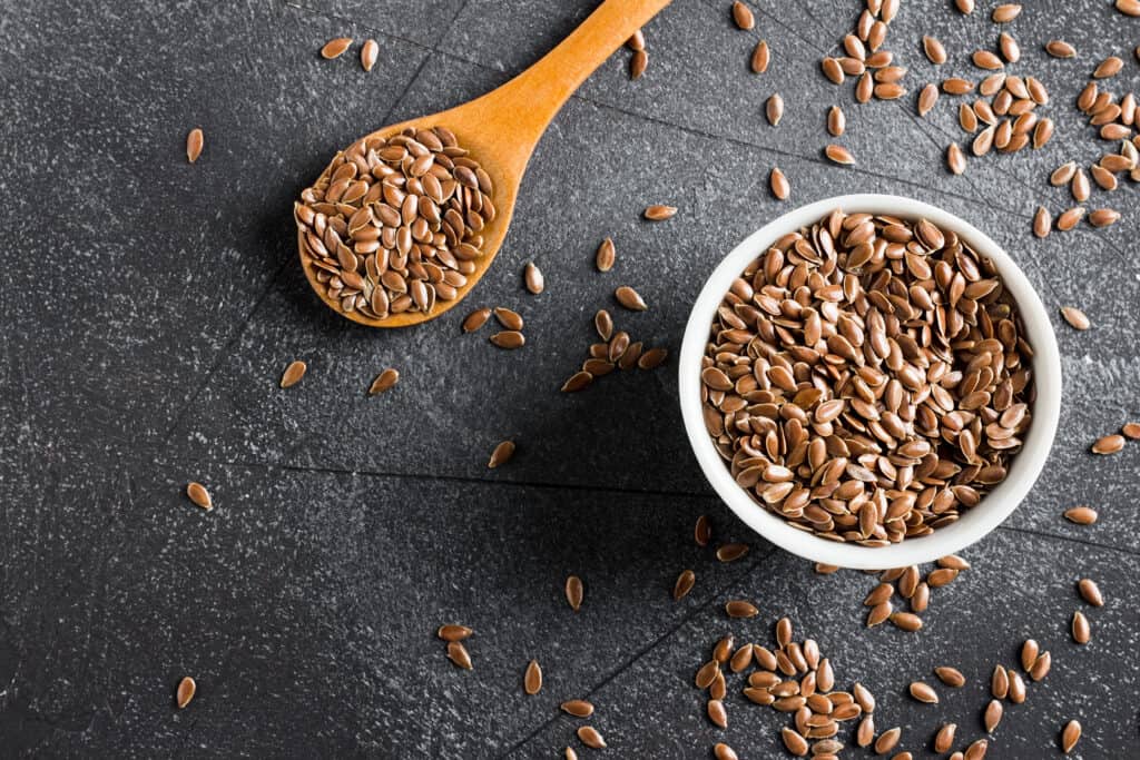 flax seeds in a small bowl and in wooden spoon