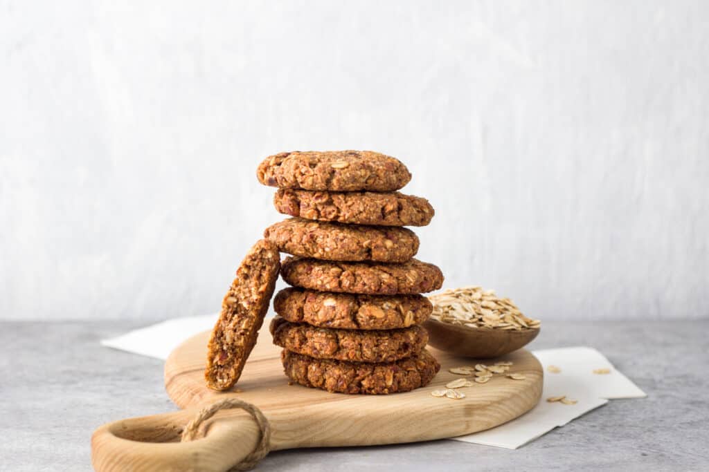 a batch of healthy gluten-free oatmeal cookies on a wooden board on a gray textured background
