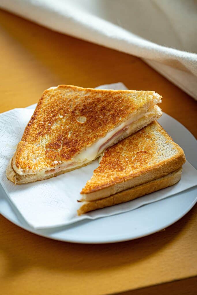 A crispy grilled cheese sandwich cut in half with cheese oozing.
