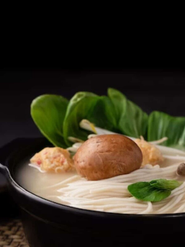 a bowl of warm cooked rice noodles topped with ginger and basil