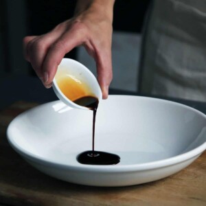 pouring homemade soy dressing in a white dish