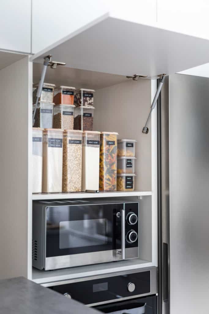 an organized kitchen cabinet containing transparent storage boxes