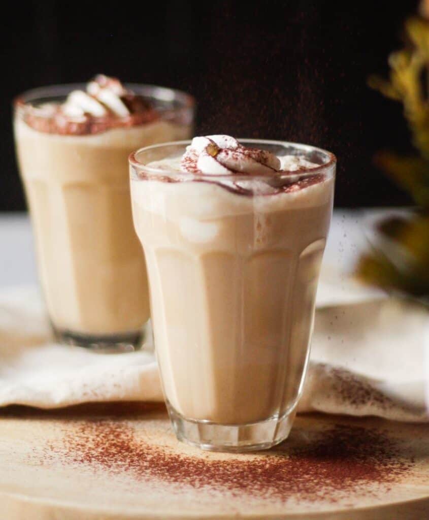 two glasses of peanut butter coffee topped with whipped cream and cocoa powder