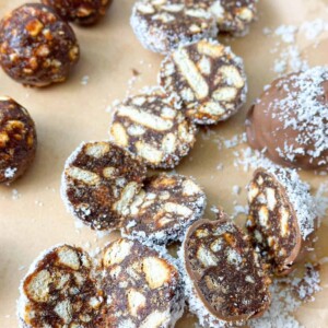 Date Balls drenched in chocolate, sprinkled with coconut, and cut in half.