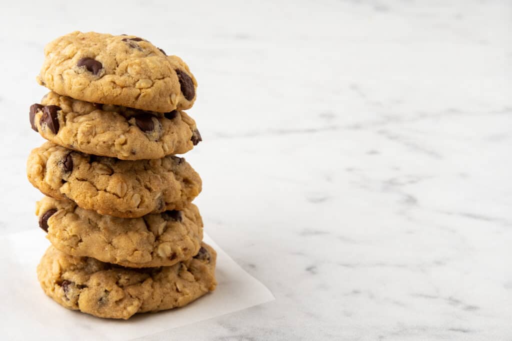 Homemade chocolate chip oatmeal cookies with hearty oats are a delightful twist on Neiman Marcus' classic recipe, offering a subtle nuttiness and chewiness. Serve warm with milk for ultimate indulgence.