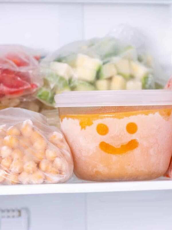 plastic bags and airtight container with different frozen vegetables in the freezer