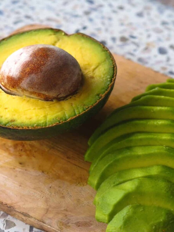 ripen avocados cut in half and sliced on a wooden board