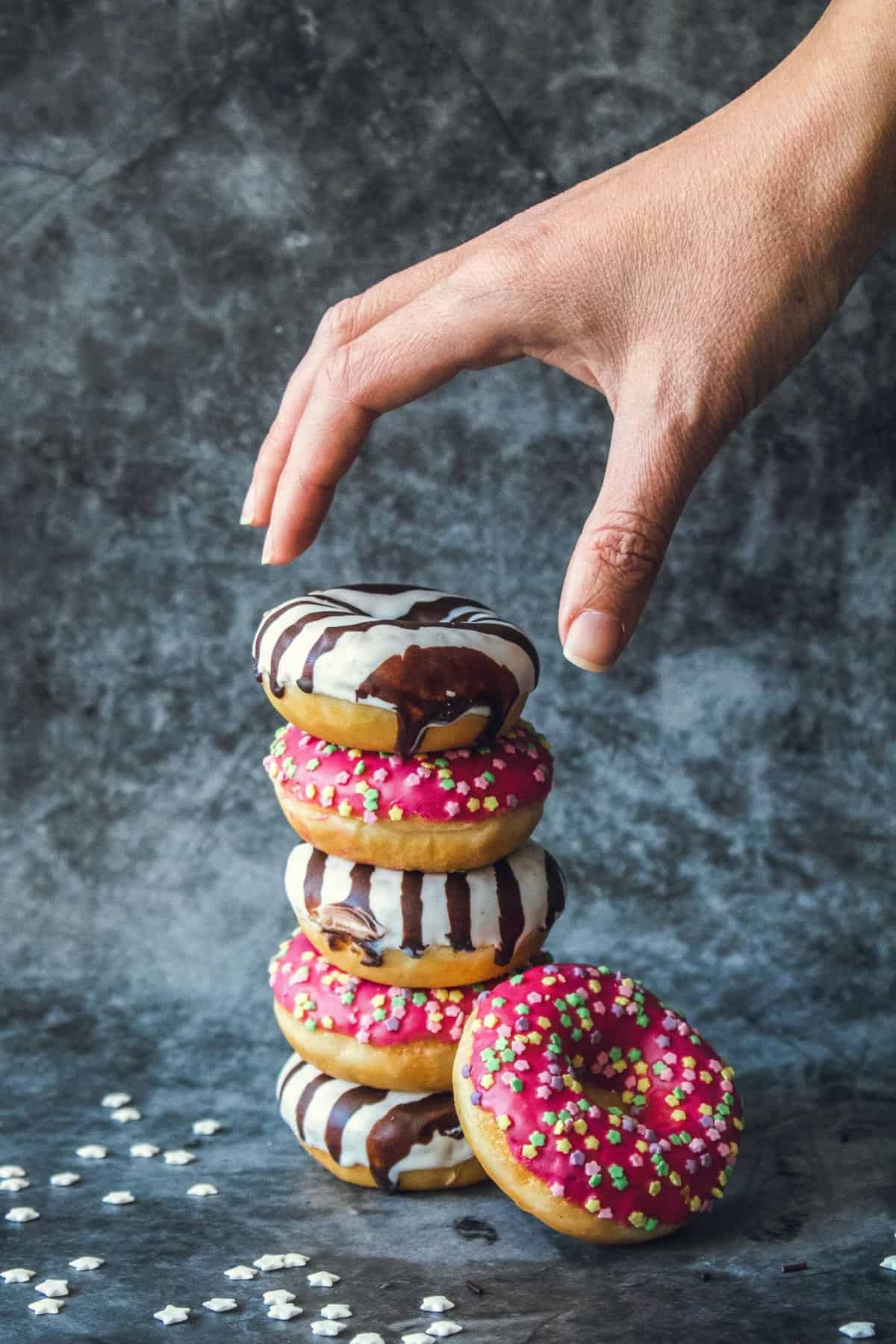 mini donuts glazed with white and black chocolate and garnished with colorful sprinkles