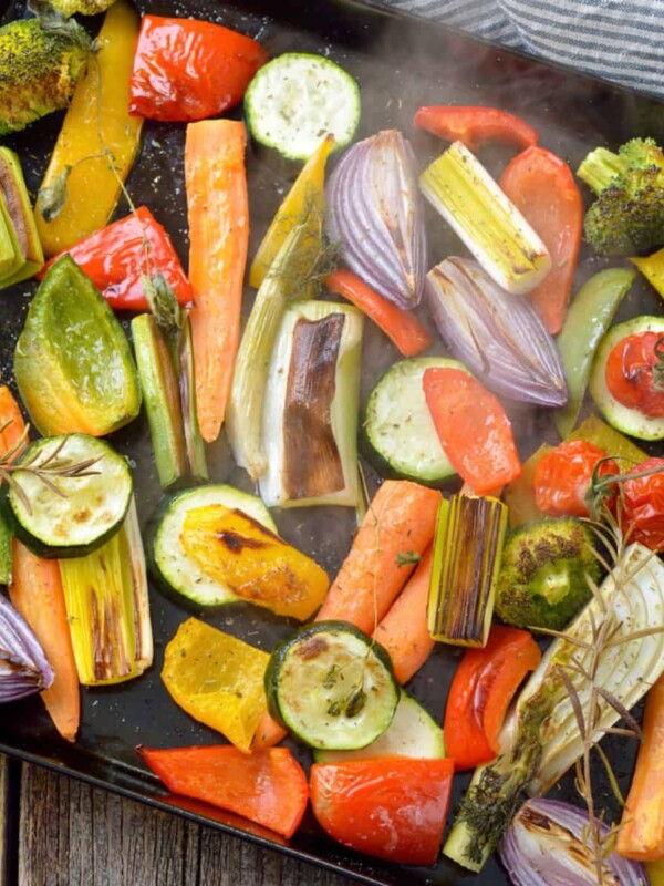 Baked colorful veggies on a baking sheet just coming steaming out of the oven