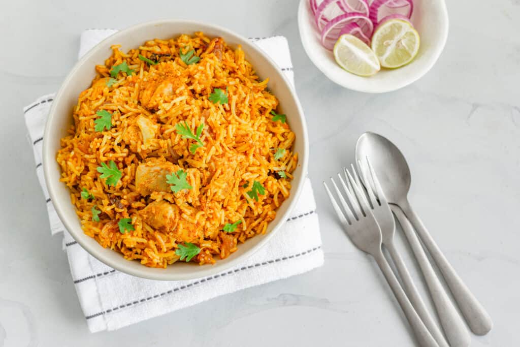 biryani rice topped with cubed chicken breasts and some chopped parsley