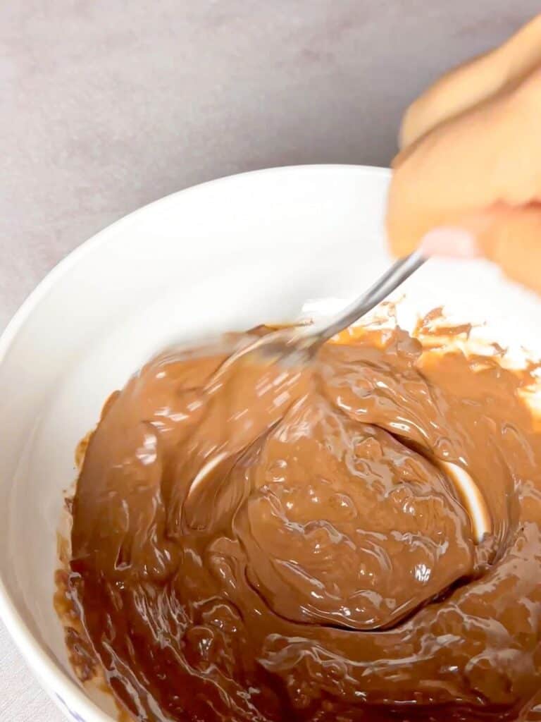 Molten chocolate is being mixed with coconut butter in this bowl.