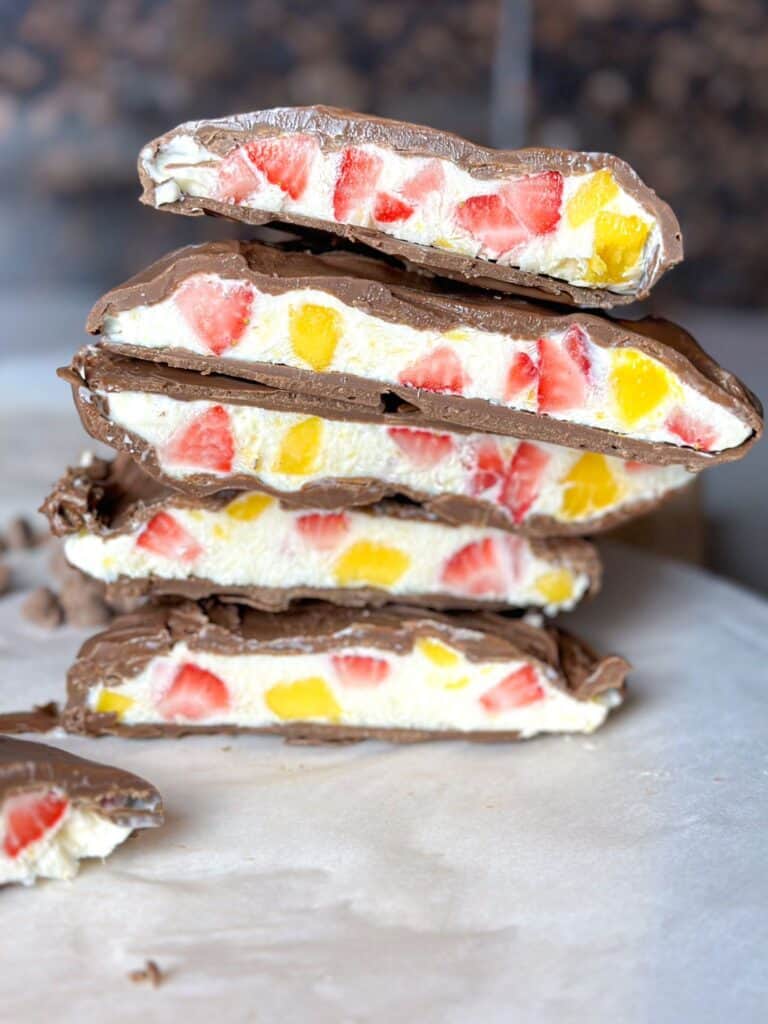 Close photo of sliced chocolate covered bars, showing the inside filling of yogurt, strawberries, and mango. 