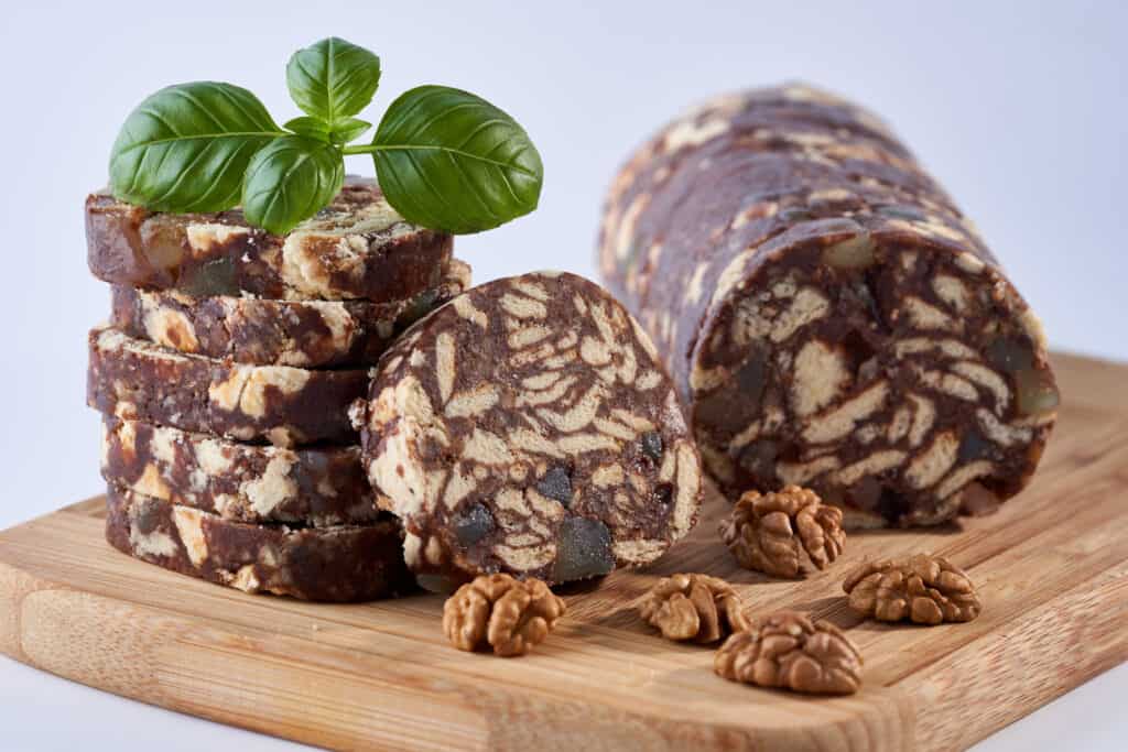 no bake lazy cake slices on a wooden cutter alongside some walnuts.