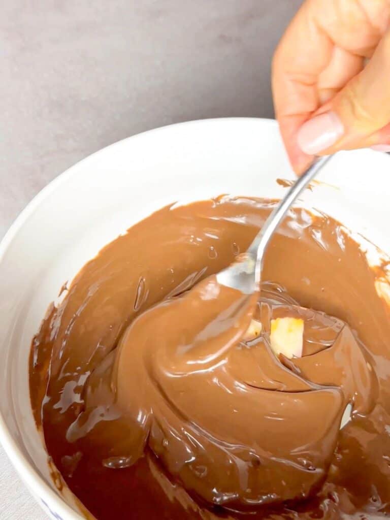 The chocolate and butter mix is being mixed and microwaved to get a smoother consistency.