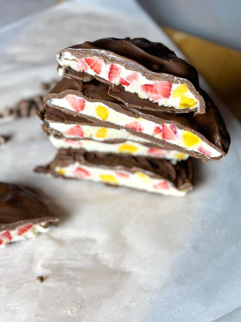 Close photo of sliced chocolate covered bars, showing the inside filling of yogurt, strawberries, and mango. 