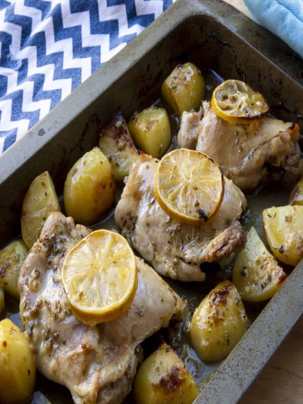 a pan of oven-baked Greek recipe made up of chicken thighs marinated in lemon and herbs