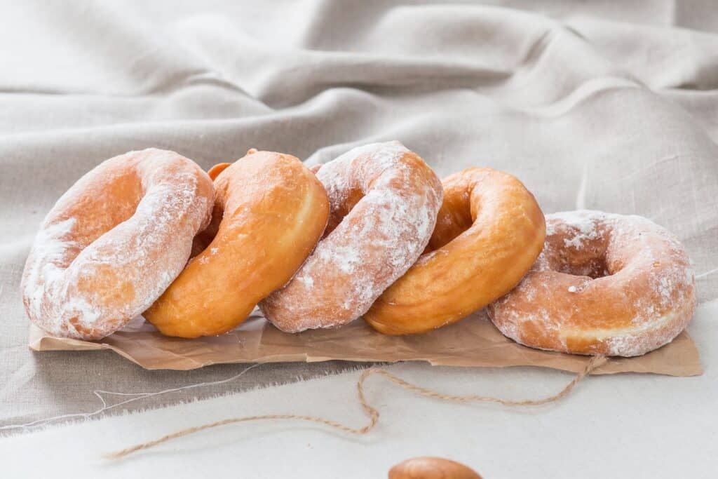 5 air fryer biscuit donuts made to golden perfection and topped with powdered sugar