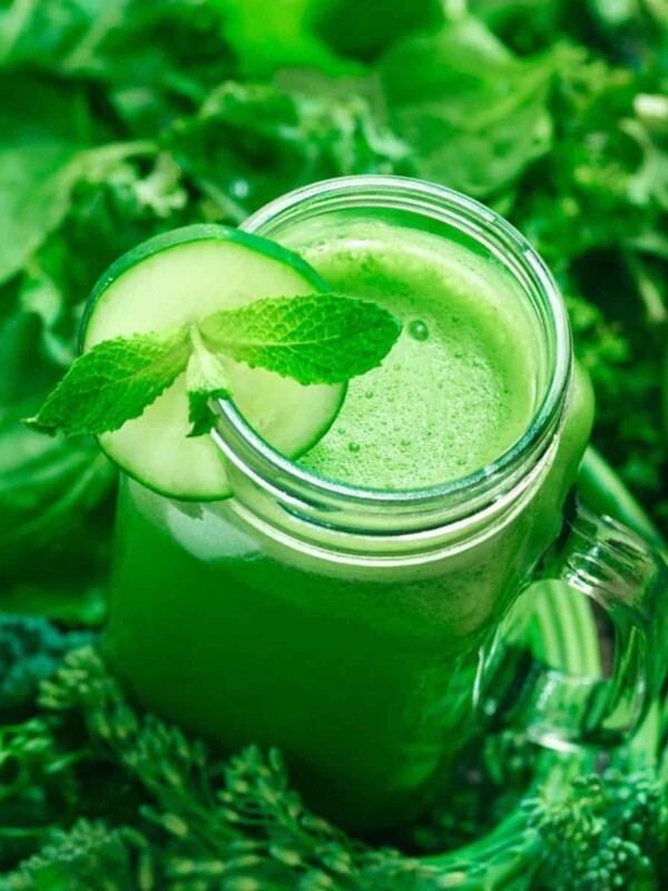 a glass jar of apple and kale juice with cucumber mint garnish