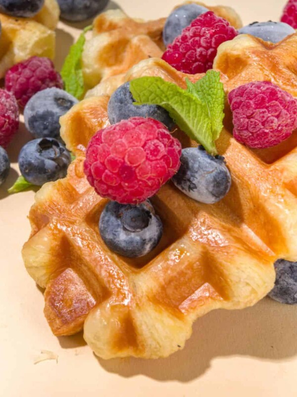 puff pastry waffles topped with whipped cream and fresh fruits such as blackberries and raspberries