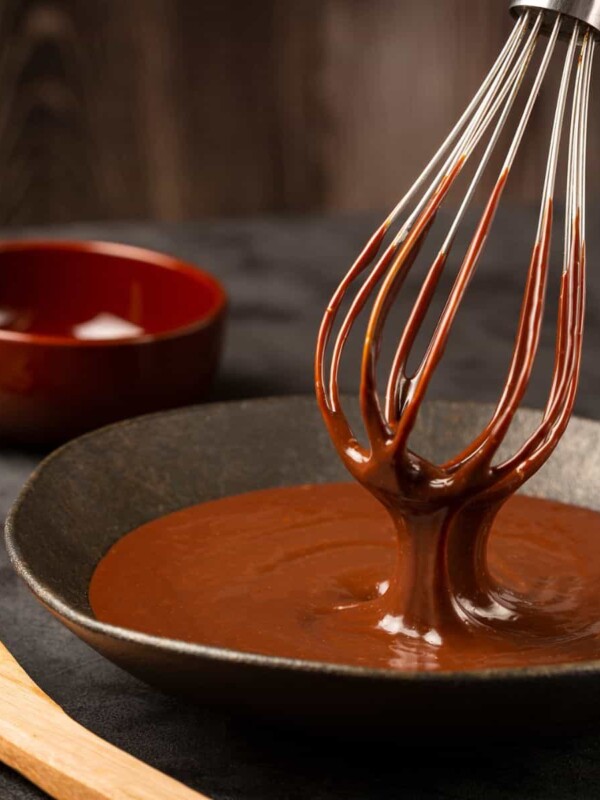A black pot filled with chocolate ganache and a whisk emerging from within.