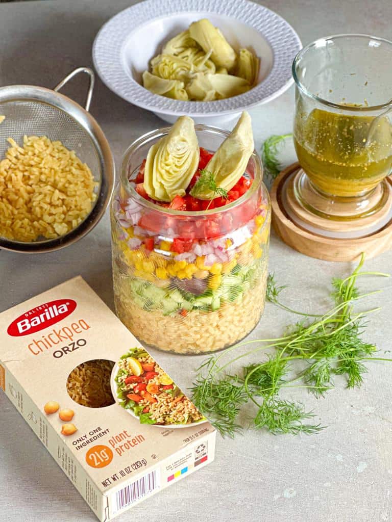 a jar of orzo pasta salad, chickpea orzo pasta box, and vinaigrette dressing