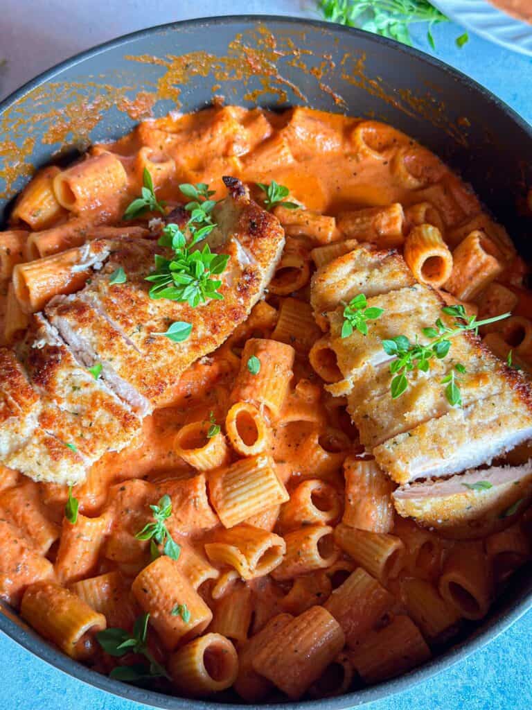 rigatoni pasta with pink sauce topped with chicken breasts