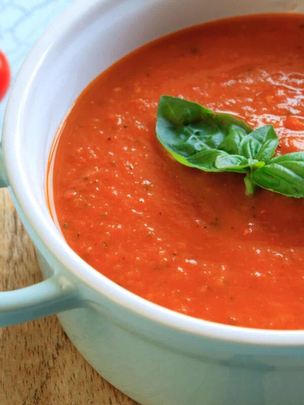 a bowl of warm tomato soup decorated with fresh basil leaves on top