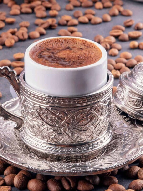 traditional Turkish coffee served in metal traditional cup with coffee beans on the floor