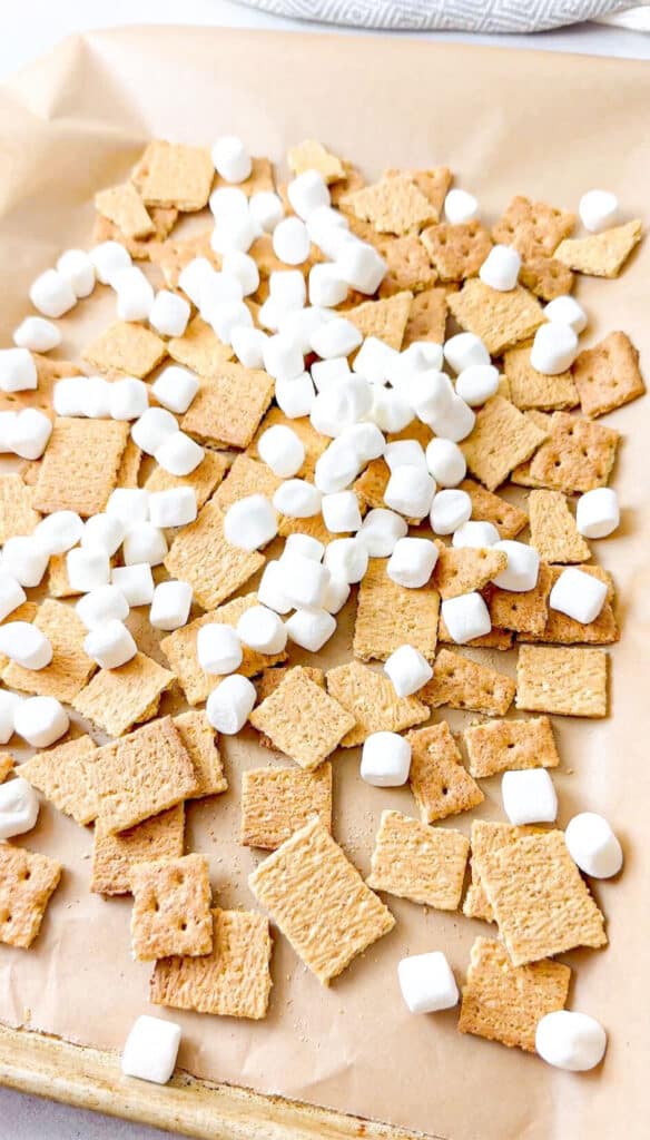 a pan with a layer of graham crackers pieces and mini marshmallows