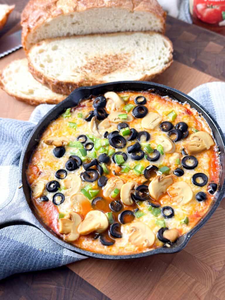 A pan of delicious pizza that's topped with black olives, green peppers and  mushrooms, and soaked in a yummy Prego Spicy Marinara sauce. 