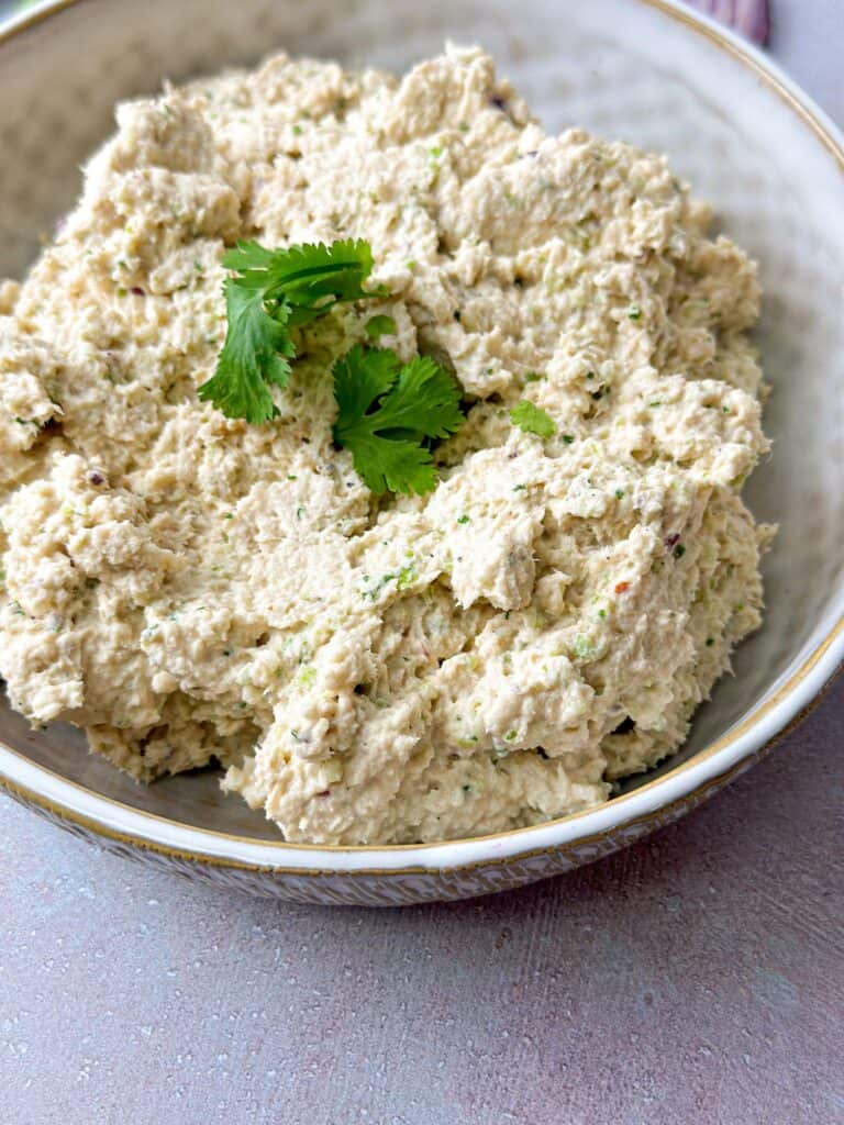 tuna and pesto mixture in a white bowl topped with fresh cilantro leaves