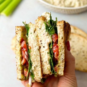 viral tunacado sandwich split into two pieces with fresh veggies and tuna-pesto combination