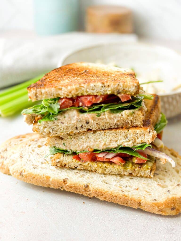 pesto-tuna mixture topped with veggies between two slices of bread