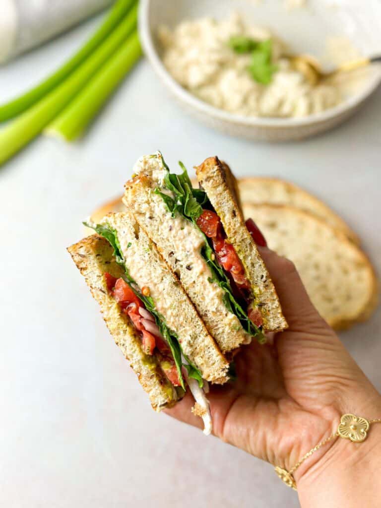 a woman holding the viral tunacado sandwich split into two pieces