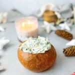 A warm and golden-brown bread bowl filled with creamy spinach dip.