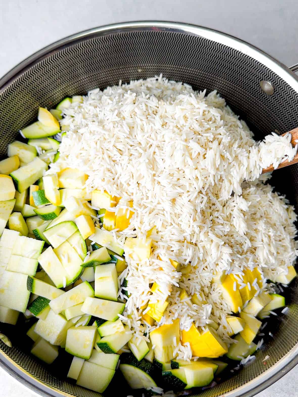 washed and drained basmati rice added on green and yellow squash cubes