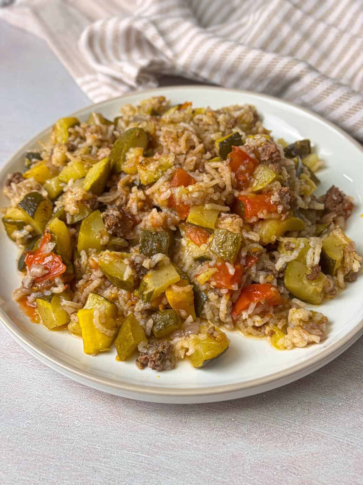 A close-up of a plate of unstuffed squash, featuring vibrant green zucchini slices sautéed with ground beef, onions, garlic, and tomatoes,