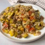 A close-up of a plate of unstuffed squash, featuring vibrant green zucchini slices sautéed with ground beef, onions, garlic, and tomatoes,