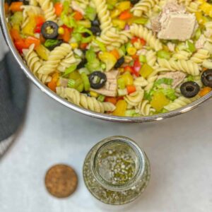 Healthy Pasta Salad with albacore tuna and on the side a glass bottle with creamy italian dressing