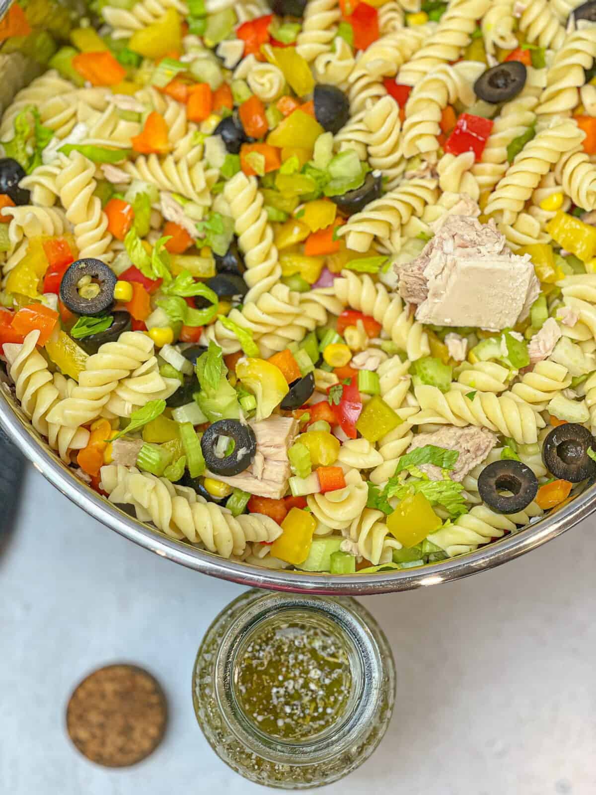 Large bowl of healthy pasta salad with tuna and an Italian creamy vinaigrette dressing in a bottle