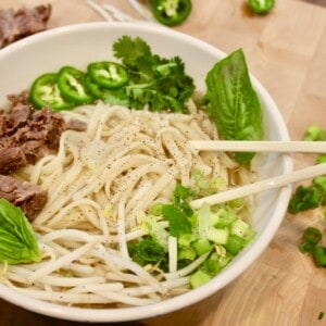 Traditional Vietnamese Pho Soup finalized with a handful of fresh herbs like cilantro.
