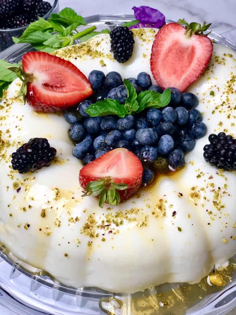 Ashta Panna Cotta topped with some berries and a drizzle of simple syrup and decorated with mint leaves