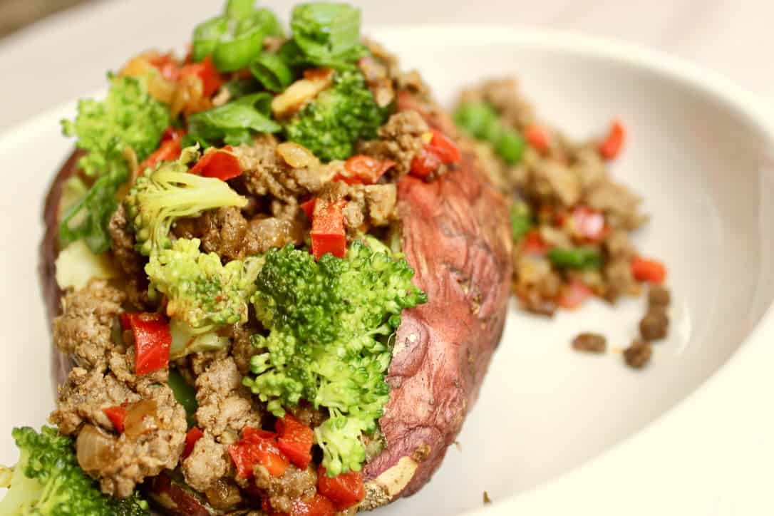 A medium sweet potato with broccoli and beef with garlic, onion, and red bell pepper and s seasoned with chili powder, ground cumin, and salt baked in the oven