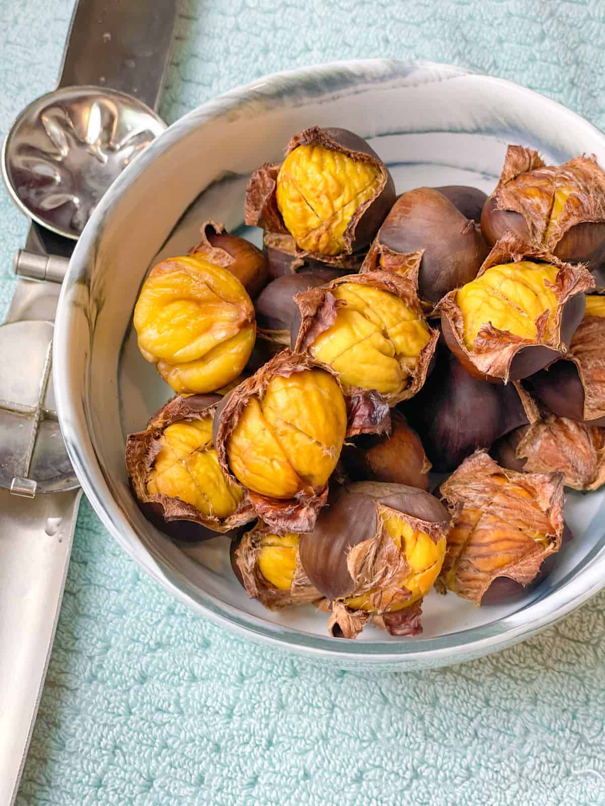 A dish full of yellow roasted chestnuts with curled shells