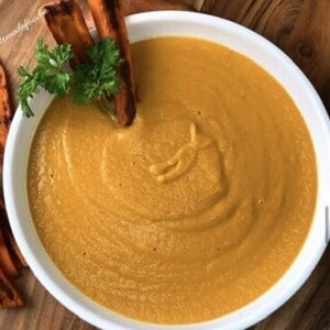 Carrot Sweet Potato Thai Soup with two carrots and parsley in a bowl