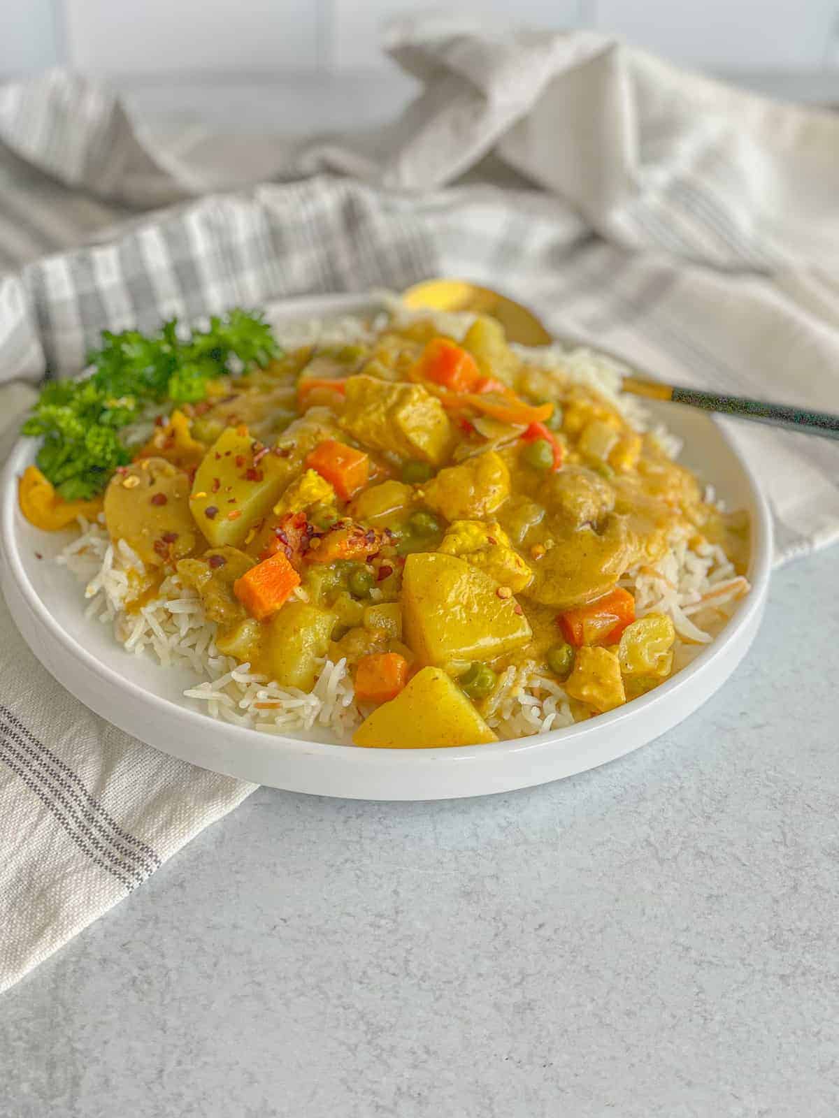 a dish of chicken vegetable curry recipe served on a bed of rice and sprinkled with chili flakes