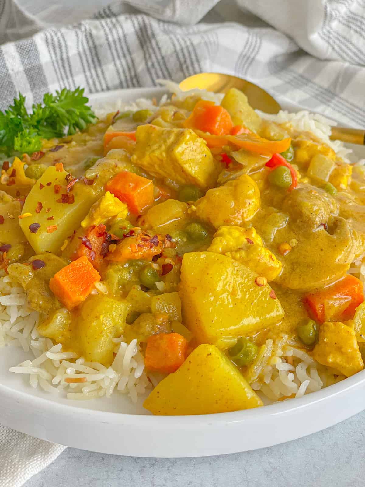 a close view of a dish of warm chicken curry with vegetables served on a bed of white rice