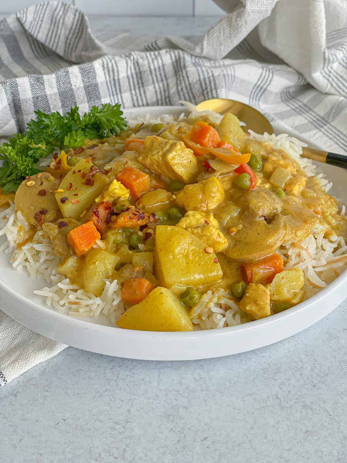 creamy chicken vegetable curry served on a bed of white rice and sprinkled with chili flakes